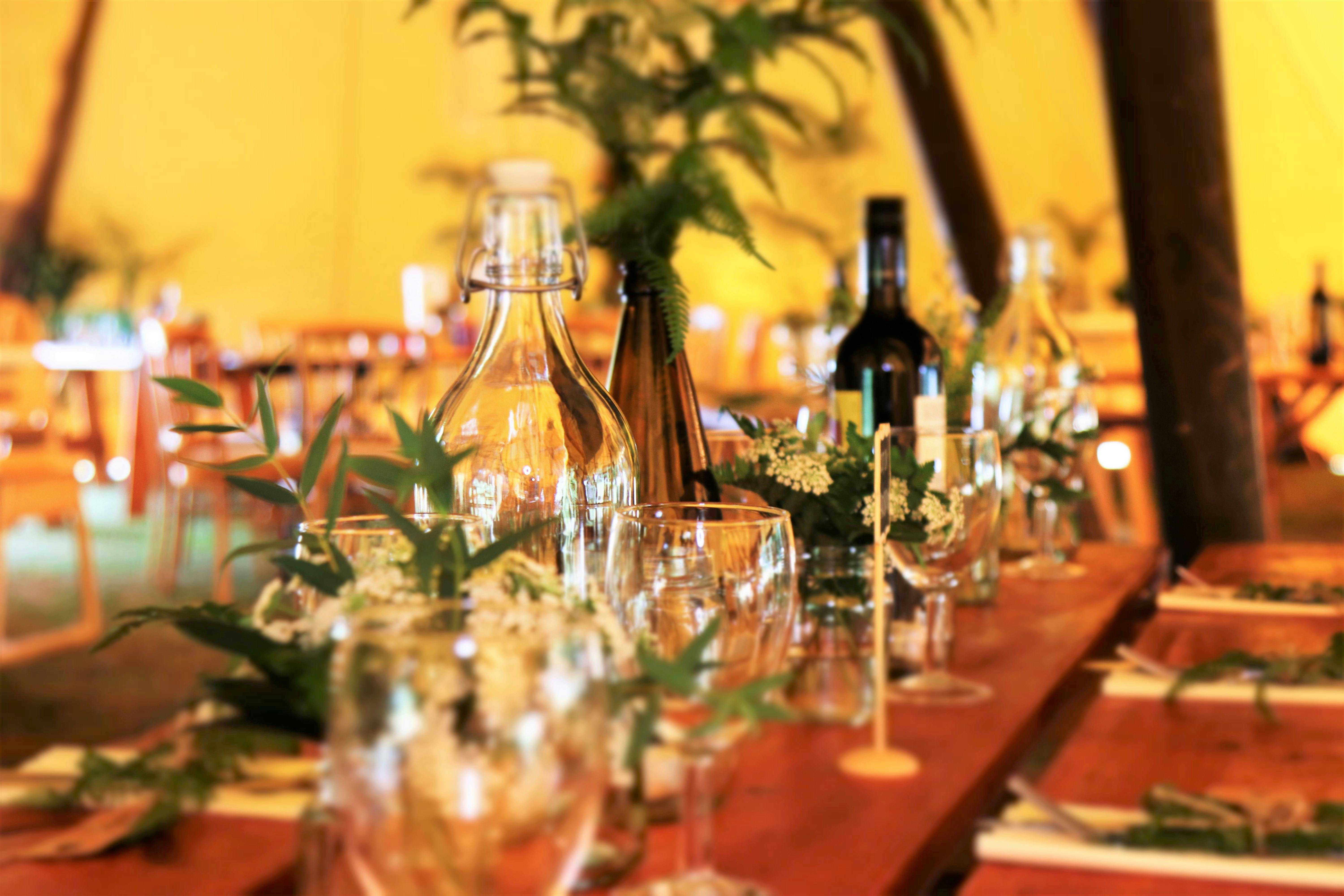 Beautifully arranged dining table with greenery and glassware in a warm indoor setting.